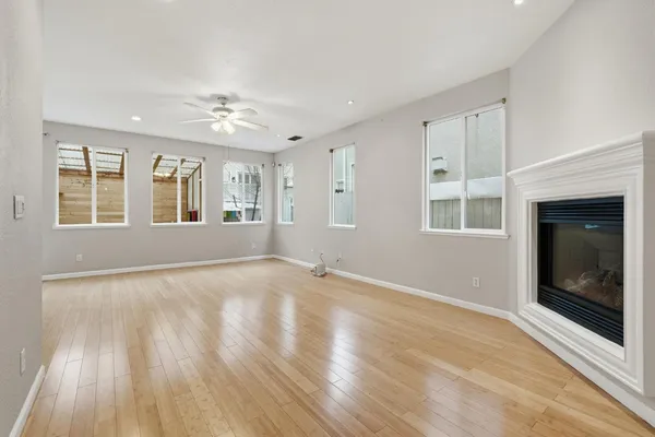 a view of an empty room with a window and wooden floor