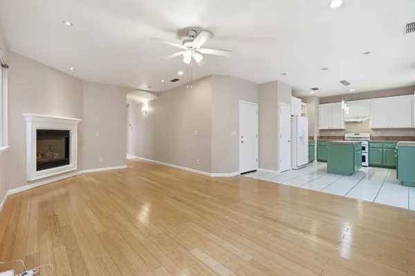 a view of an empty room with a fireplace and chandelier fan