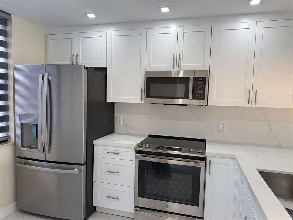 1520 Whitehall Drive, Unit 306 Davie, FL 33324 - Photo 11 of 42 a kitchen with stainless steel appliances white cabinets white stove a microwave and a refrigerator