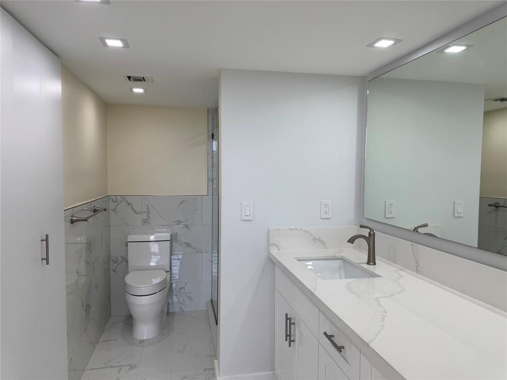 1520 Whitehall Drive, Unit 306 Davie, FL 33324 - Photo 22 of 42 a spacious bathroom with a granite countertop sink a toilet and a mirror