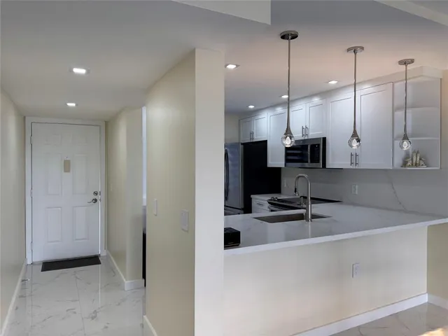 a kitchen with kitchen island a sink stainless steel appliances and a counter top space