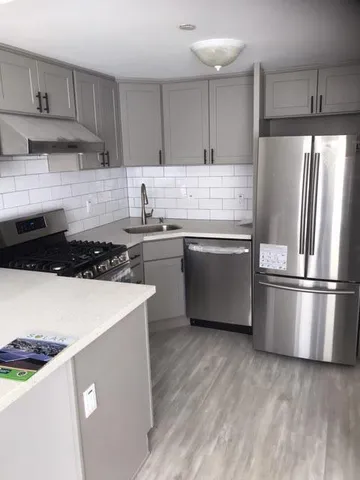 a kitchen with stainless steel appliances a refrigerator a stove a sink and white cabinets