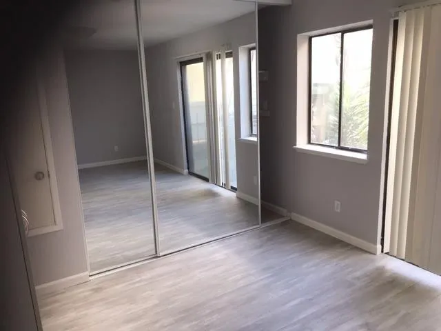 an empty room with wooden floor and windows
