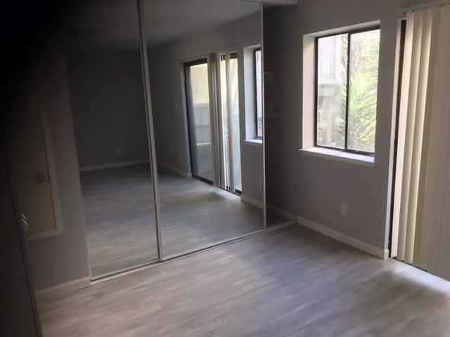 an empty room with wooden floor and windows