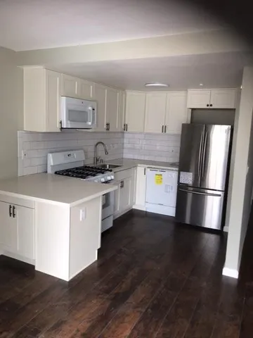 a kitchen with stainless steel appliances a refrigerator a stove a sink and white cabinets