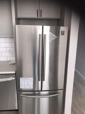 a view of a refrigerator in kitchen and an empty room