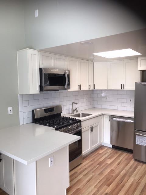 28 Houston Street San Francisco, CA 94133 - Photo 22 of 32 a kitchen with granite countertop a stove top oven a sink dishwasher and a microwave oven on the wooden floor