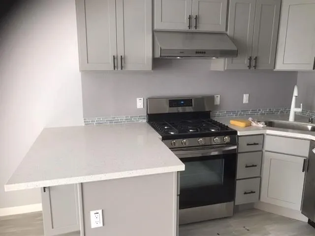 a kitchen with stainless steel appliances a stove and white cabinets