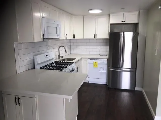 a kitchen with stainless steel appliances granite countertop a refrigerator a stove a sink and a microwave