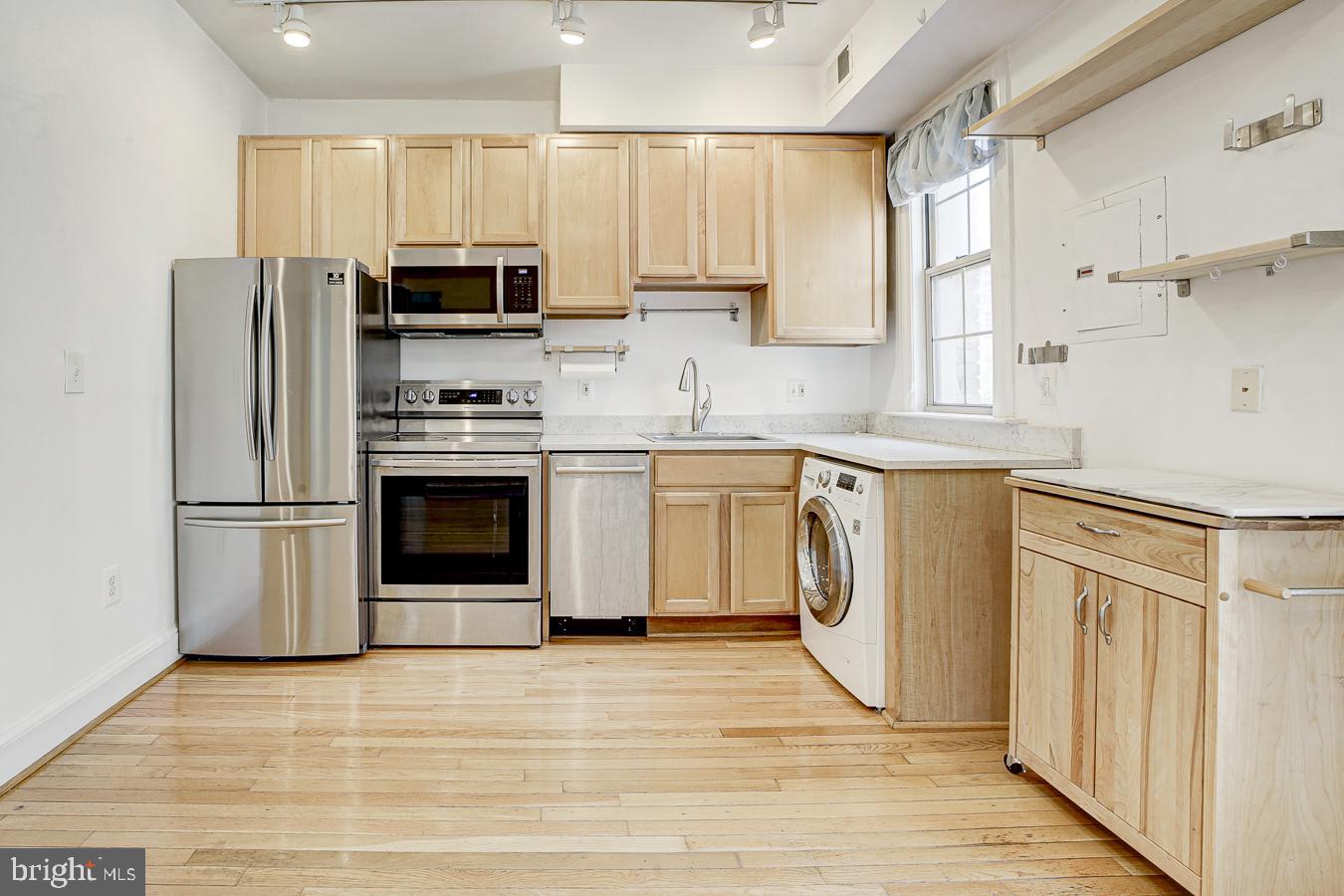 1401 Columbia Road Northwest, Unit 219 Washington, DC 20009 - Photo 9 of 33 a kitchen with stainless steel appliances a stove a sink a refrigerator white cabinets and wooden floor
