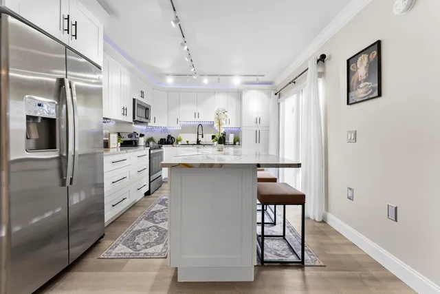 a kitchen with stainless steel appliances kitchen island granite countertop a table chairs refrigerator and sink