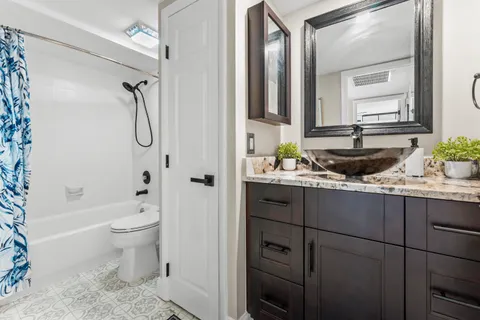 a bathroom with a granite countertop sink a toilet and shower