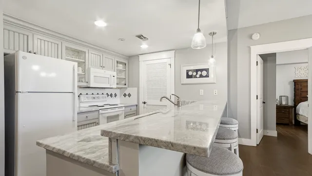 a kitchen with stainless steel appliances granite countertop a refrigerator a stove a dining table and chairs with wooden floor