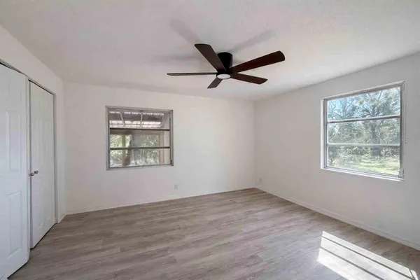 a view of an empty room with a window and wooden floor