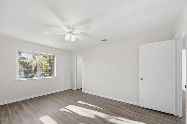 an empty room with windows and ceiling fan