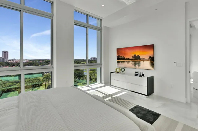 a living room with a flat screen tv a floor to ceiling window and a flat screen tv