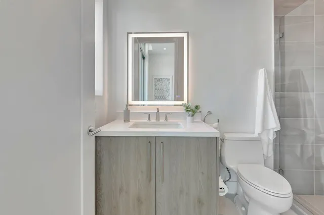 a bathroom with a granite countertop toilet sink and mirror