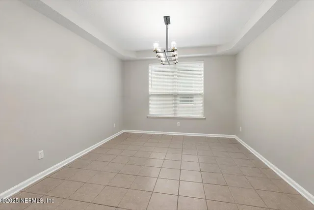 an empty room with windows and chandelier fan