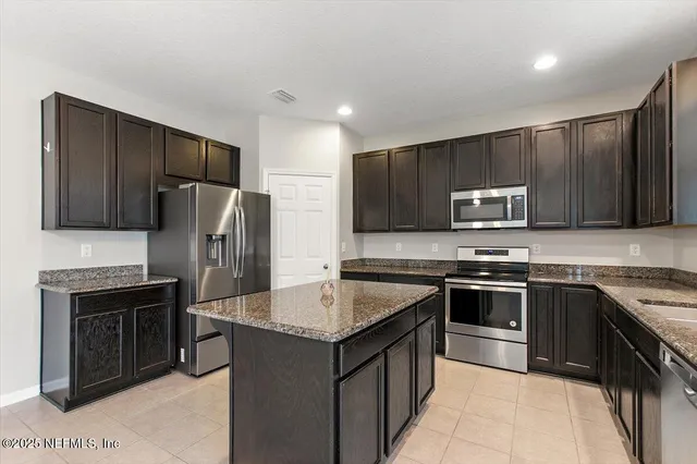 a kitchen with stainless steel appliances granite countertop a stove top oven a sink dishwasher a refrigerator and a microwave