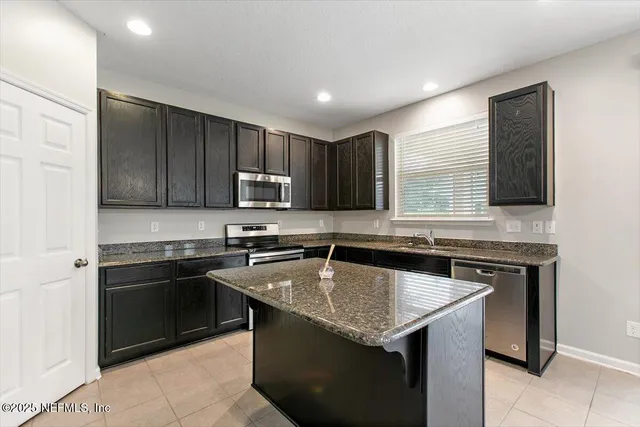 a kitchen with granite countertop stainless steel appliances a sink stove and microwave