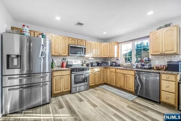 a kitchen with granite countertop stainless steel appliances a sink a window and cabinets