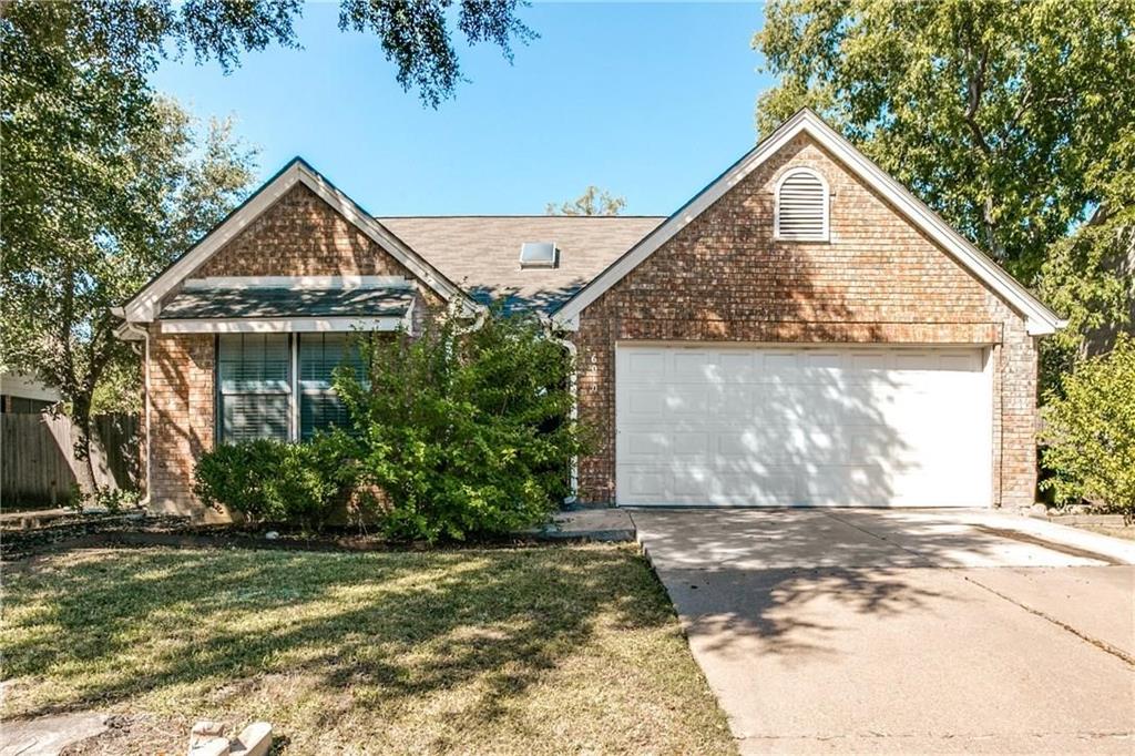 View of front facade featuring brick siding, driveway, and an attached garage
