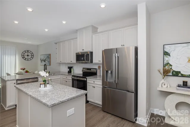 a kitchen with stainless steel appliances granite countertop a refrigerator a sink a stove a dining table and chairs