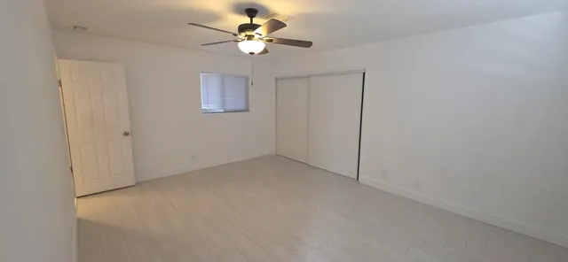 an empty room with a chandelier fan and windows
