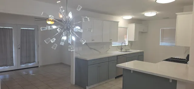 a kitchen with a sink a chandelier and cabinets