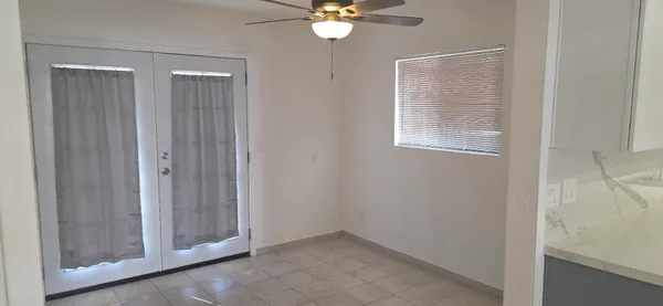 a view of an empty room with window and chandelier fan