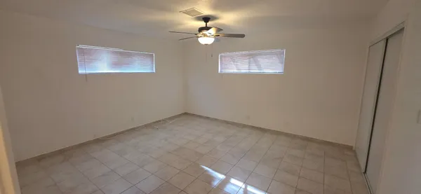 an empty room with windows and fan