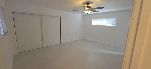 an empty room with windows and fan