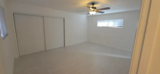 an empty room with windows and fan