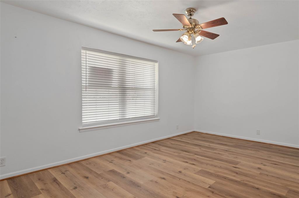 301 East 6th Street Krum, TX 76249 - Photo 19 of 29 Bedroom featuring wood-like flooring, ceiling fan and large window allowing in plenty of natural light.