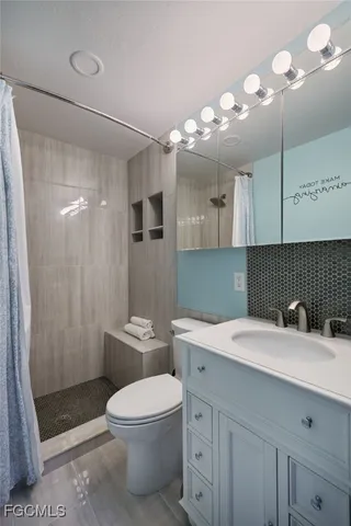 a bathroom with a sink a toilet a mirror and shower