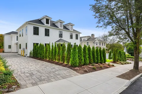 a view of a brick house with a yard and large trees