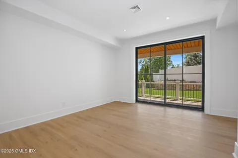an empty room with sliding glass door and garden view