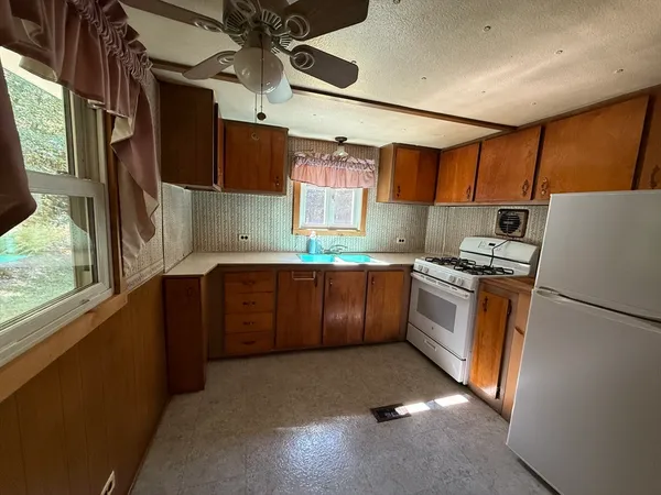 a kitchen with granite countertop a refrigerator a sink a stove a dining table and chairs