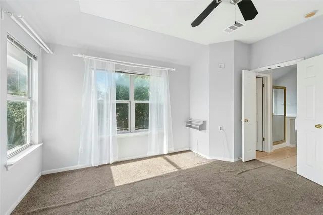 a view of an empty room with window and chandelier fan
