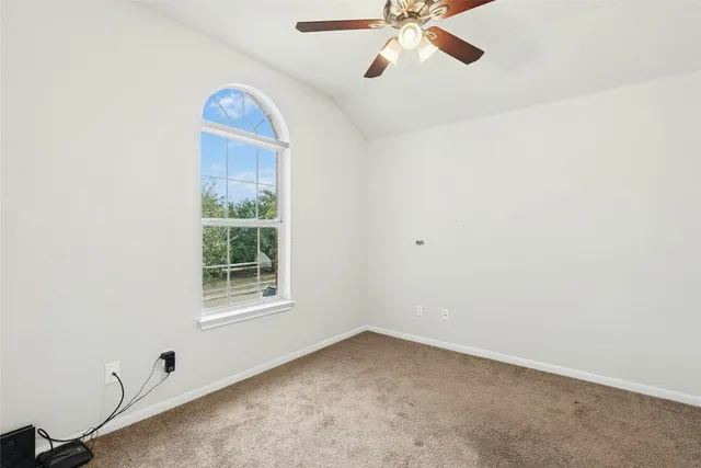 an empty room with a window and a fan