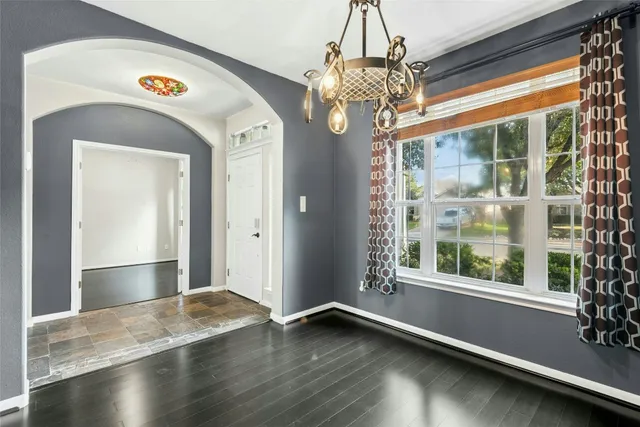 a view of a room with wooden floor chandelier and windows
