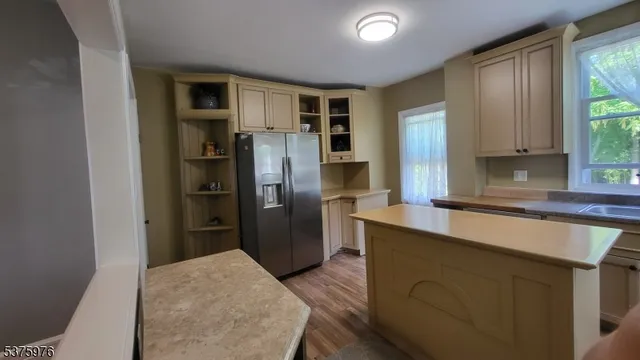 a kitchen with stainless steel appliances granite countertop a refrigerator a sink a stove a dining table and chairs with wooden floor