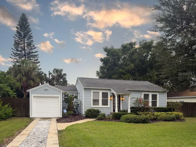 a front view of a house with a garden and trees