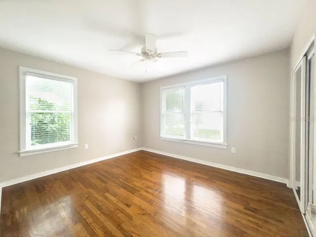a view of an empty room with wooden floor and a window