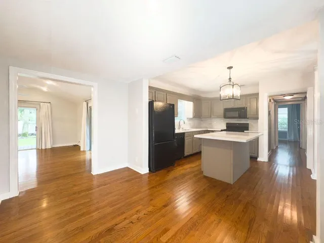 a large kitchen with cabinets wooden floor and stainless steel appliances