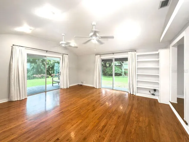 a view of empty room with wooden floor and fan