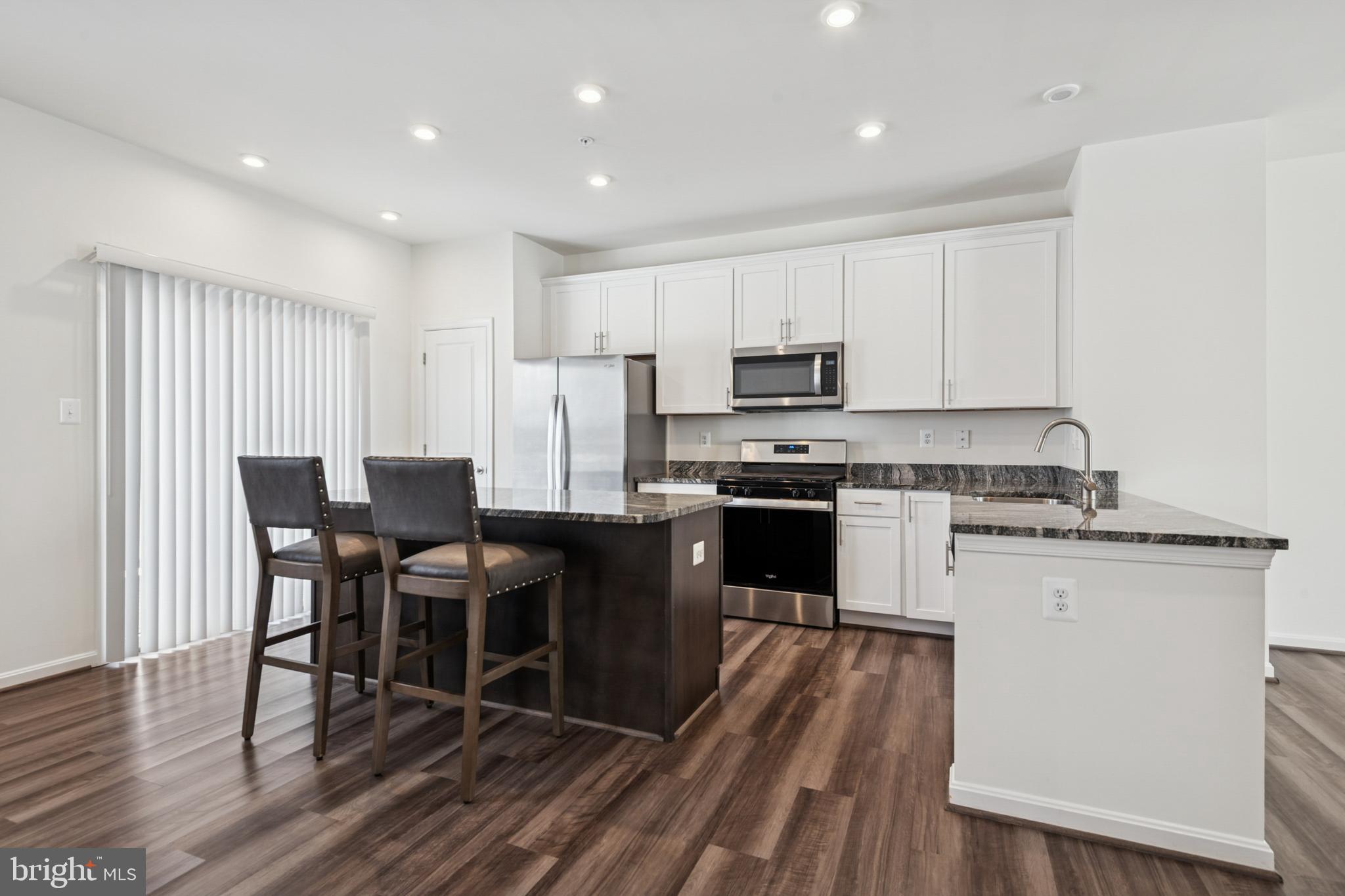 7831 Wolf Run Lane Severn, MD 21144 - Photo 2 of 30 a kitchen with kitchen island granite countertop wooden floors appliances and white cabinets