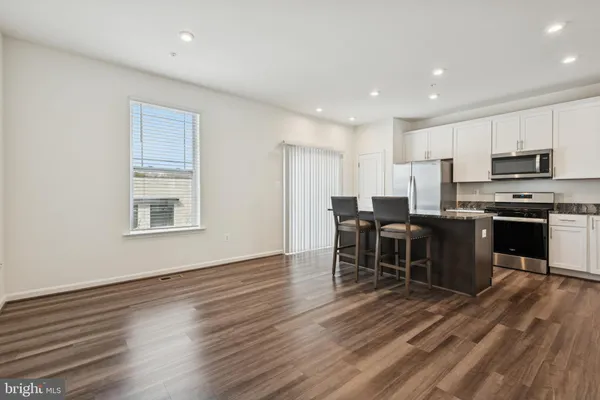 a living room with stainless steel appliances kitchen island granite countertop furniture and wooden floors