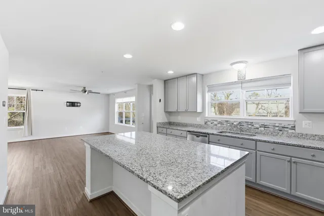 a kitchen with granite countertop a sink and a wooden floor