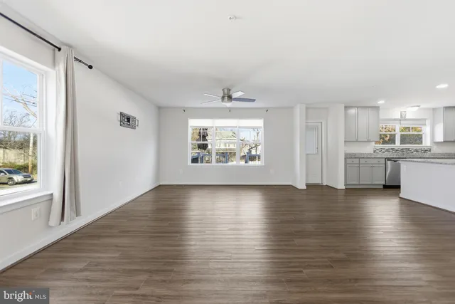 a view of an empty room with window and wooden floor